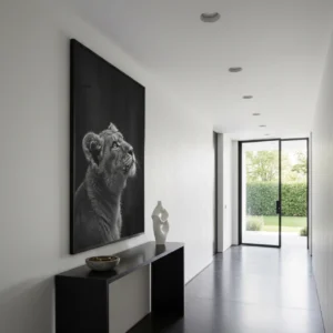 Grande affiche lion noir et blanc sur fond noir dans un couloir blanc, accrochée au-dessus d’une console noire, lumière naturelle au fond.