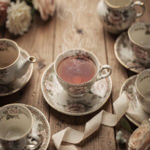 Affiche tasse de thé fumante en porcelaine florale avec service à thé et fleurs sur table en bois ambiance chaleureuse