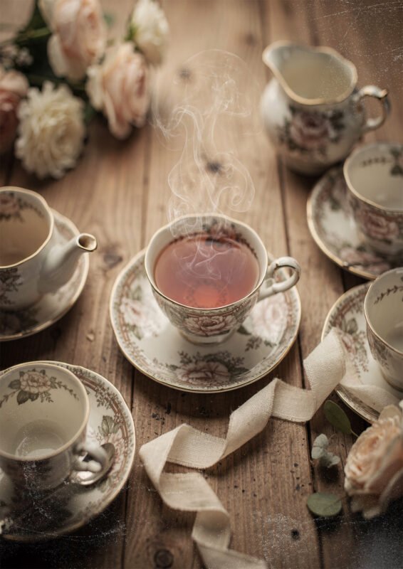 Affiche tasse de thé fumante en porcelaine florale avec service à thé et fleurs sur table en bois ambiance chaleureuse