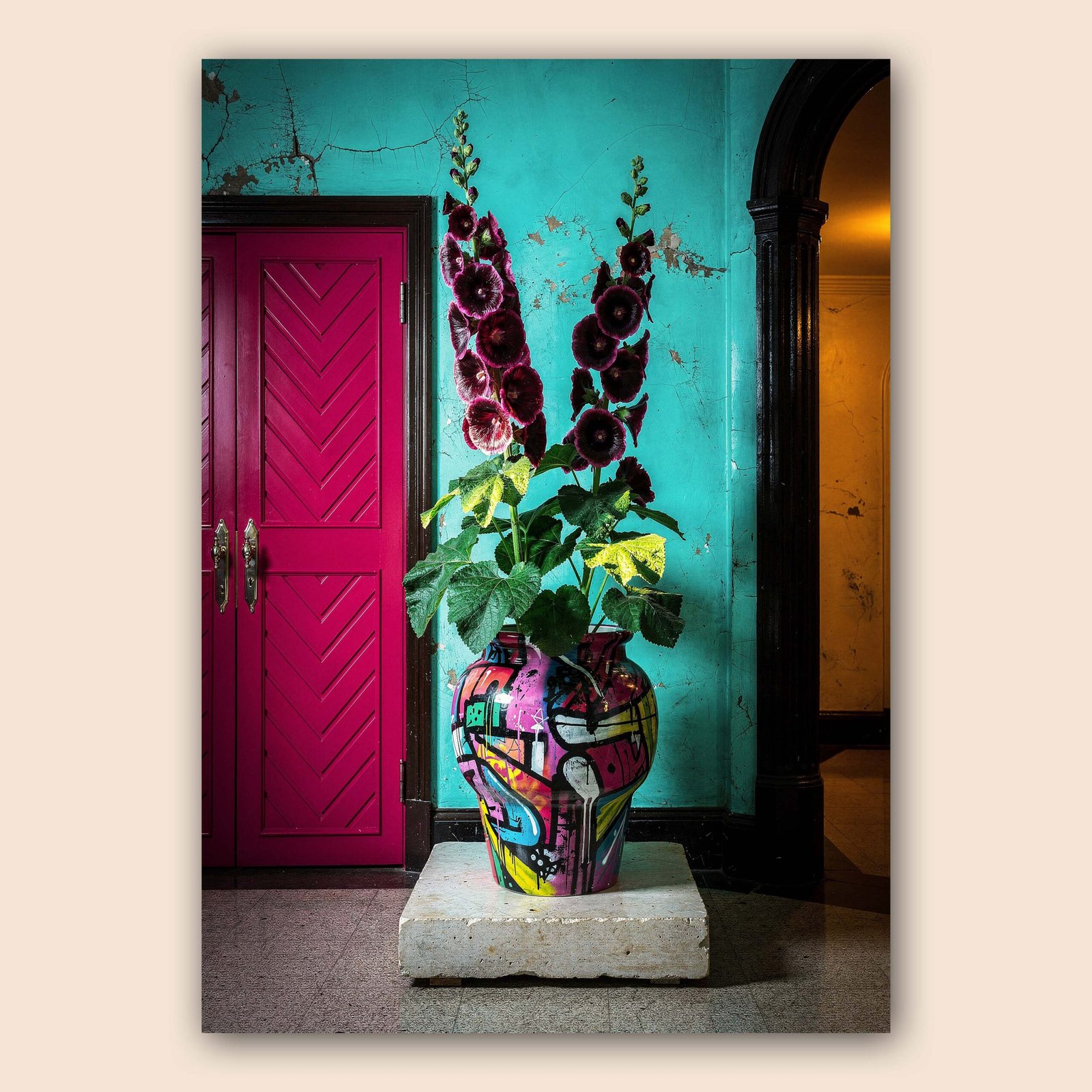 Affiche avec un vase coloré rempli de fleurs pourpres devant un mur turquoise patiné, une porte rose et une arche sombre.