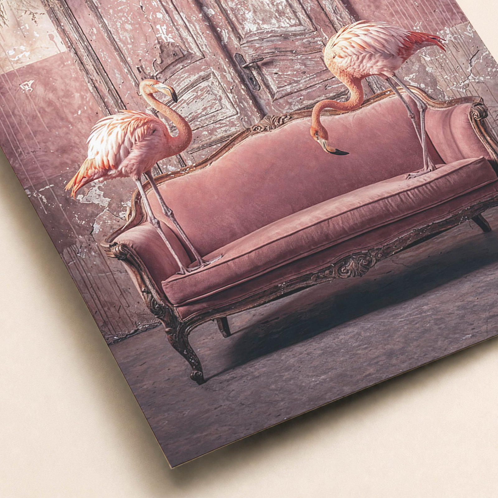 Gros plan sur une affiche avec deux flamants roses autour d’un canapé rose vintage, dans un décor patiné aux tons poudrés.