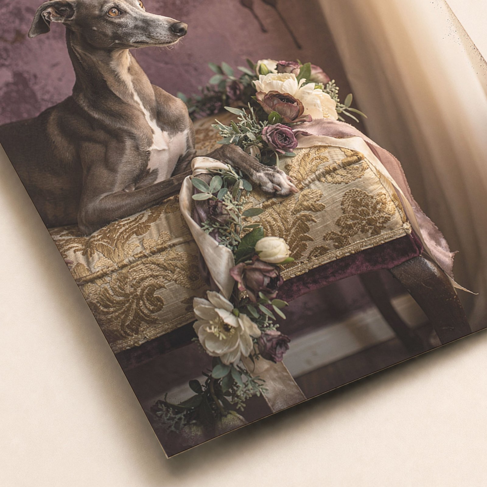 Gros plan sur une affiche avec lévrier gris allongé sur une banquette vintage, fleurs délicates et coussin brodé.